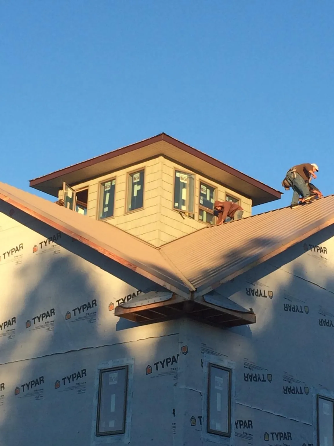 Roofers working around a rooftop cupola on a new metal roof at sunset — Roof Waterproofing in Brighton by Roofing Brothers
